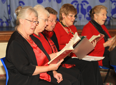 Close up of five choir members singing during a
 rehearsal.